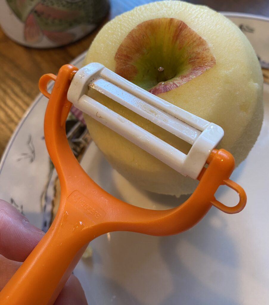 kyocera apple peeler with ceramic blade close up with peeled apple in background